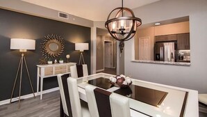 Un comedor moderno con una mesa de vidrio, sillas blancas y una lámpara decorativa.