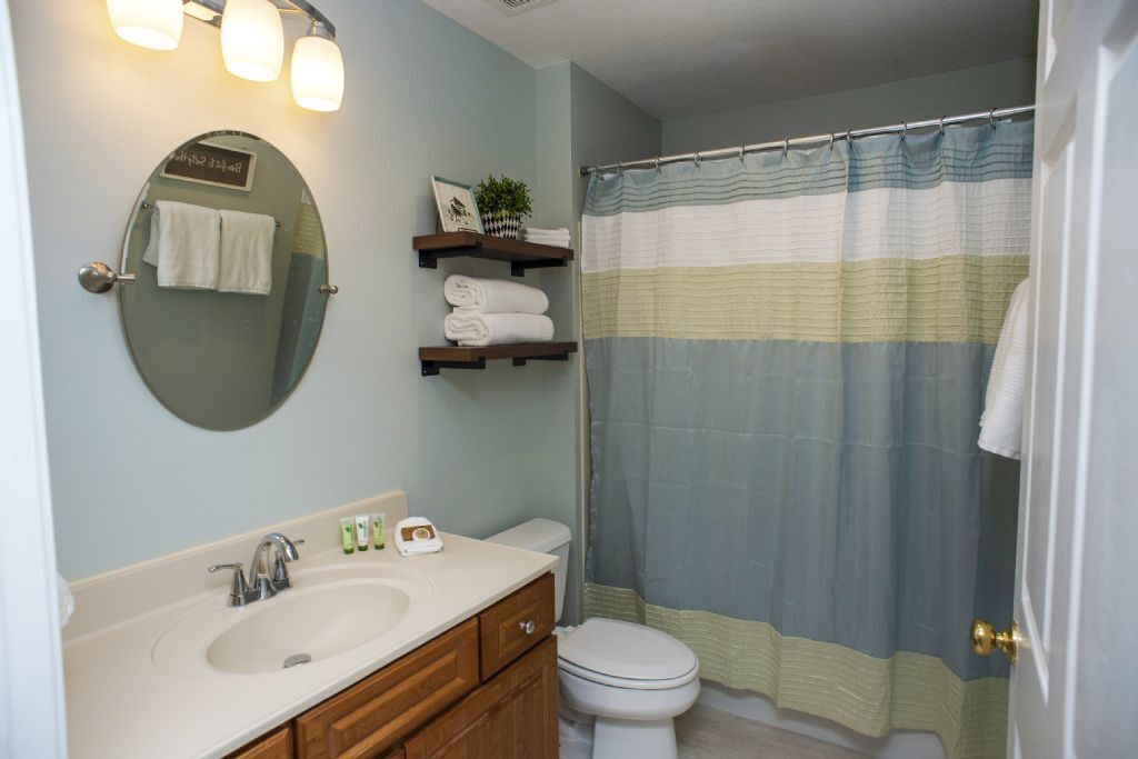 Une salle de bain équipée d’un lavabo, d’un miroir, d’un porte-serviettes et d’un rideau de douche.
