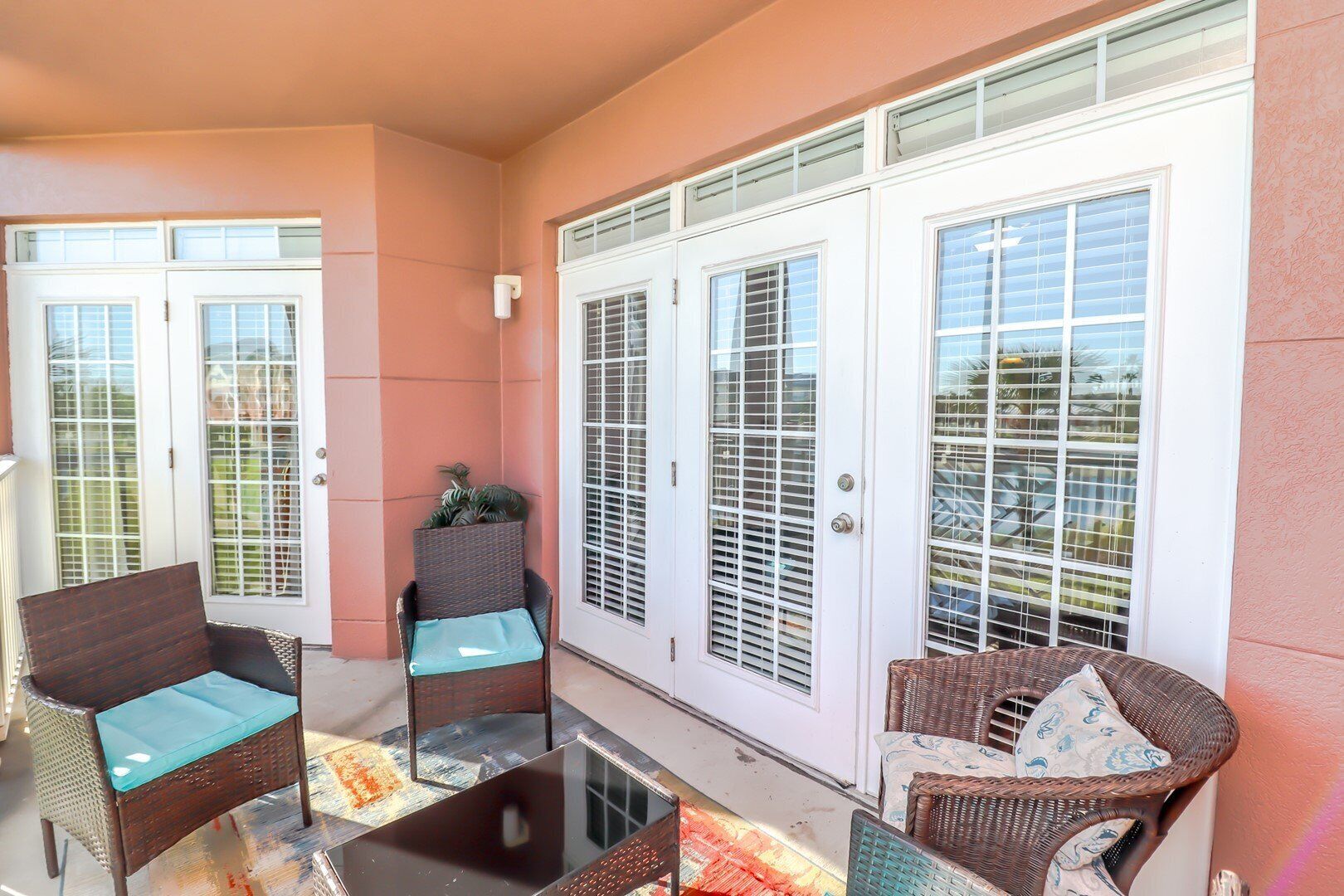 A balcony with wicker chairs, a small table, and a potted plant.