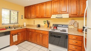 Une cuisine avec des meubles de rangement en bois, une cuisinière et un évier.