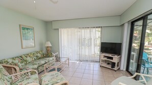 Un salon comprenant un canapé, des fauteuils, un téléviseur et un balcon avec vue.
