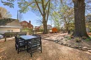 Un espace extérieur aménagé en terrasse, avec une table et des chaises, entouré de gravier et d’arbres.