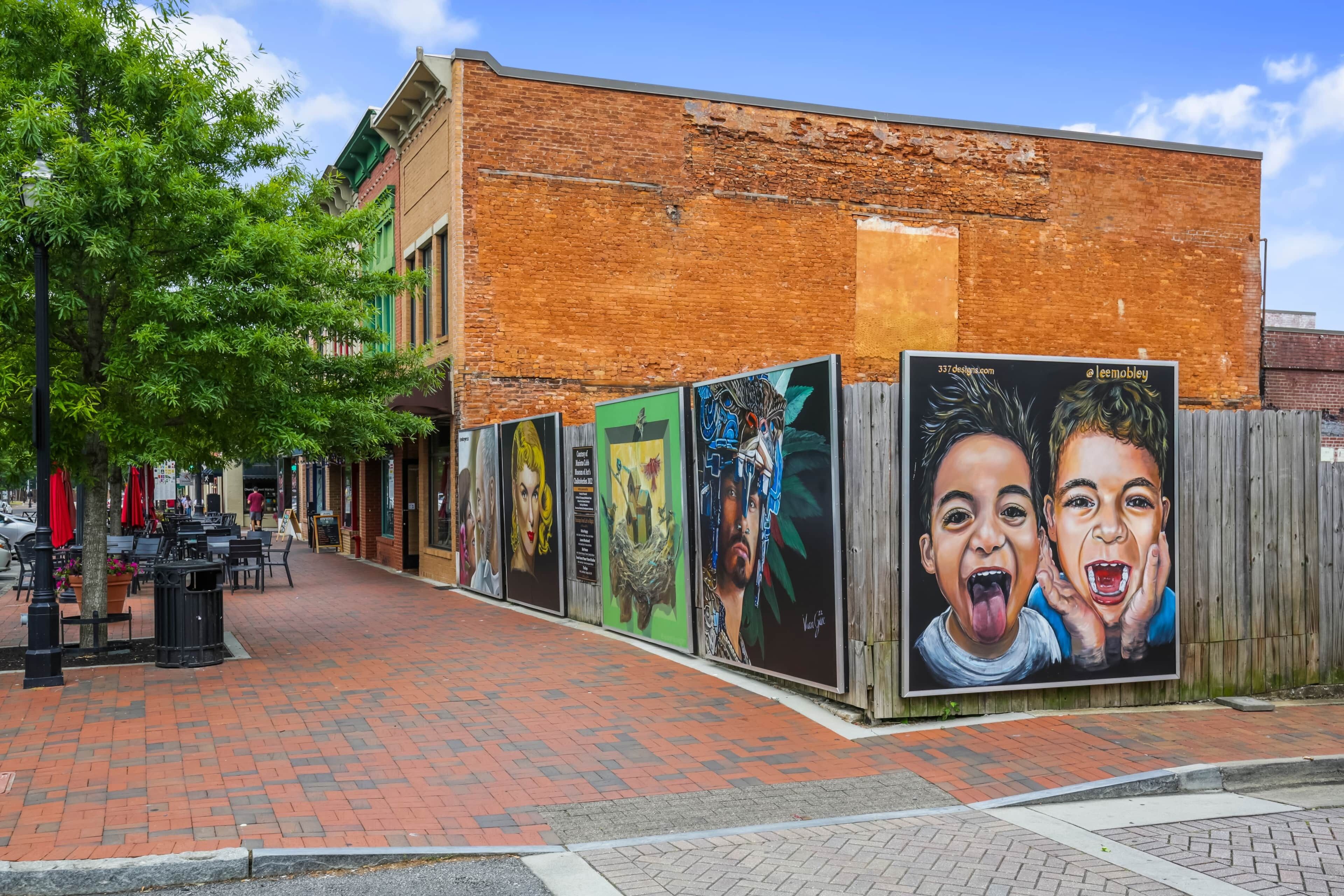 Un bâtiment en briques orné d’une rangée de peintures murales colorées sur son mur latéral.