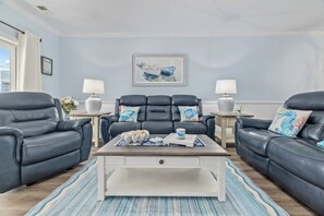 A living room with two black leather sofas, a white coffee table, and a framed painting on the wall. - Myrtle Beach 3BR w/ Lake & Pool Views + Golf (Myrtle Beach)
