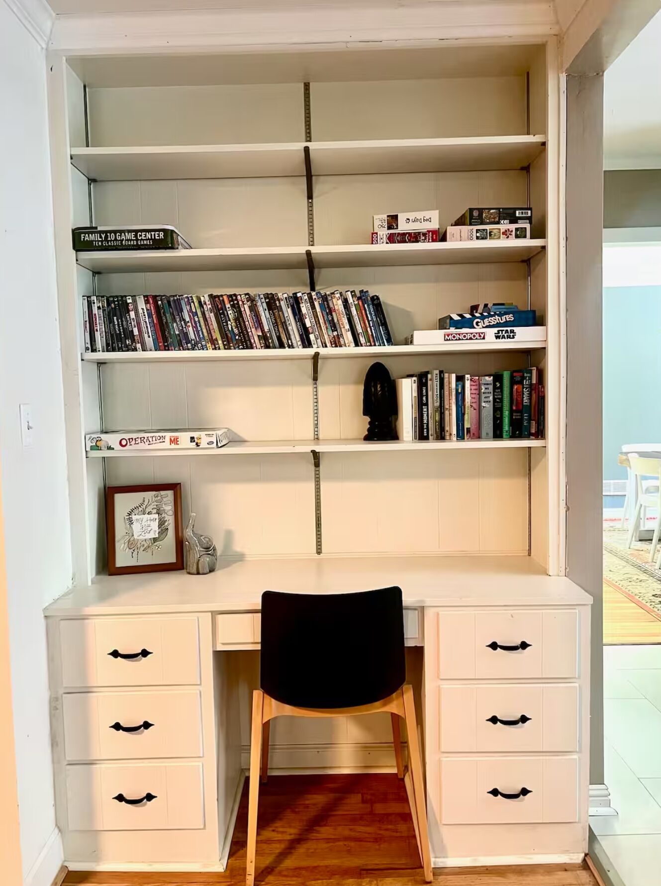 A study area with a desk, chair, and shelves containing books and board games.