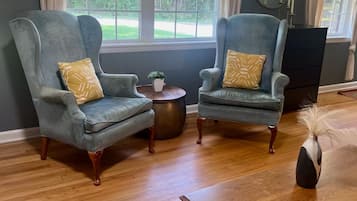 Une pièce comprenant deux fauteuils, une petite table ronde et une table basse en bois.