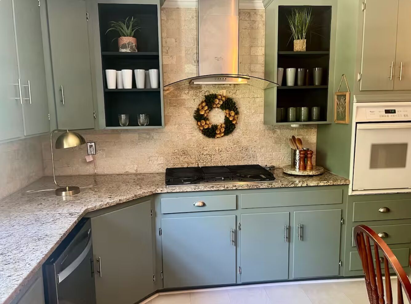 A kitchen with light blue cabinets, a granite countertop, a built-in stove, and a wall-mounted oven.