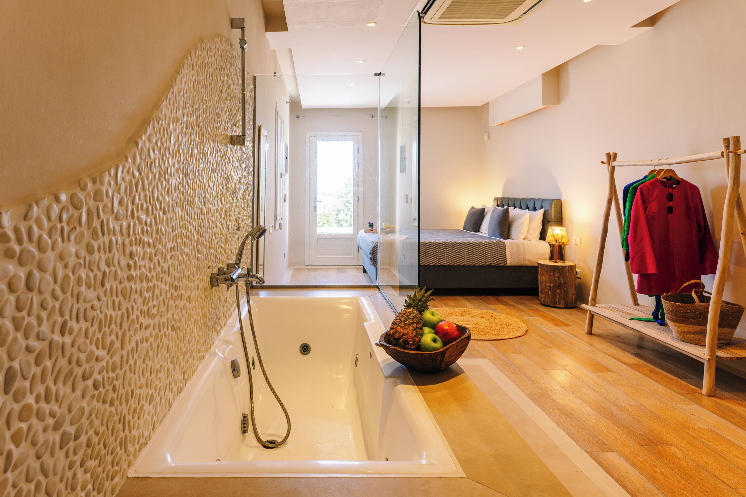 A modern bathroom with a freestanding bathtub, a wooden floor, and a fruit bowl on the floor.