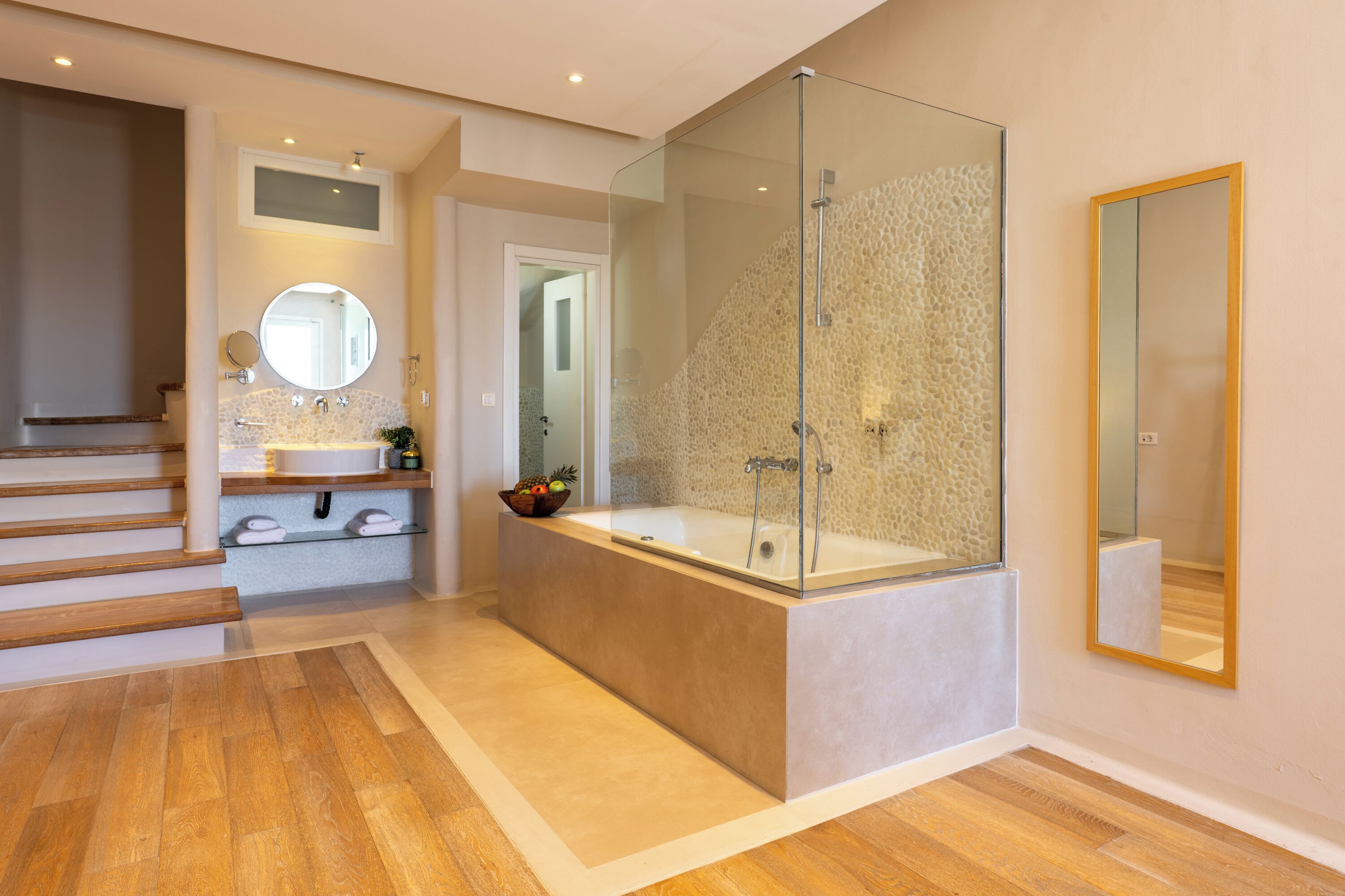 A modern bathroom with a glass-enclosed shower, a freestanding bathtub, and a vanity with a mirror.