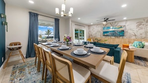 A dining area with a long table set for six, surrounded by wooden chairs. - Waterfront Stunner! Heated Pool+Spa+Sauna+Firepit+ Playground! (West Palm Beach)