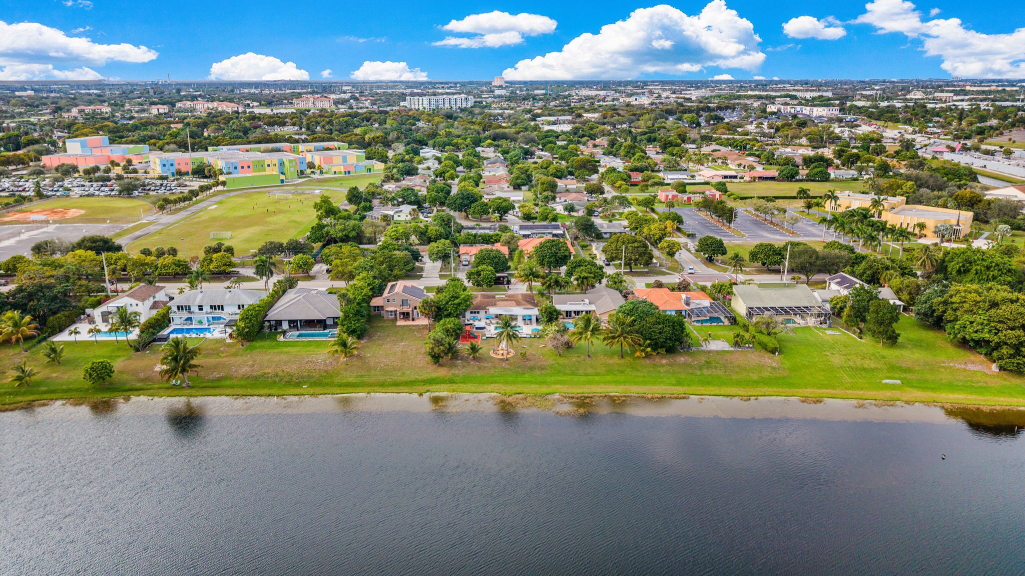 An aerial view of a residential area with houses, a large body of water, and a distant cityscape.