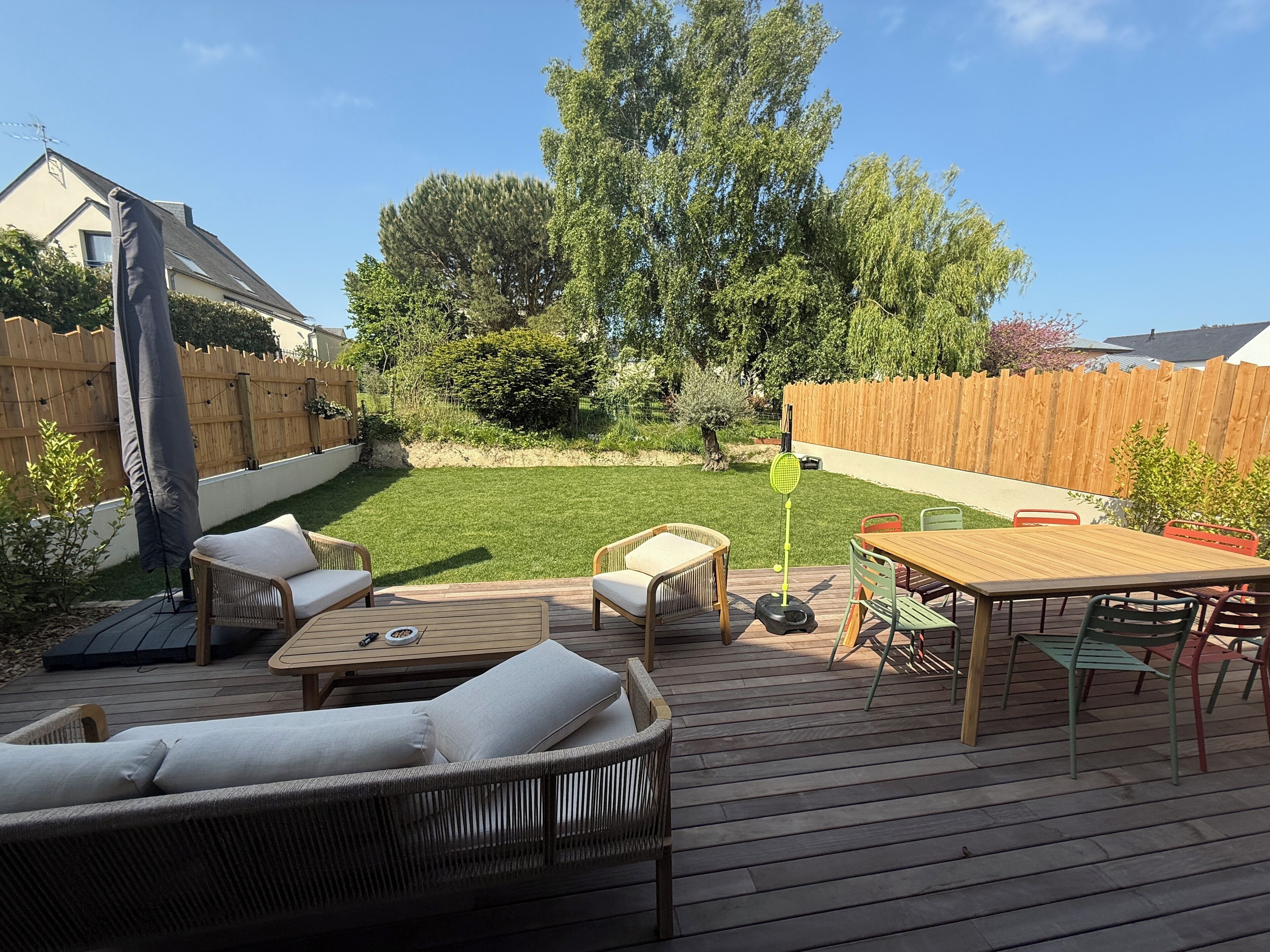 A wooden deck with outdoor furniture, including a sofa, chairs, and a table.