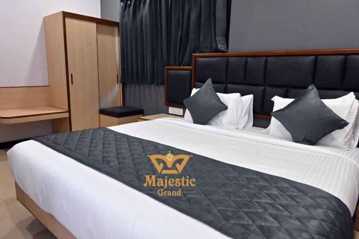 Habitación de hotel con una cama grande, un armario, una mesita de noche y una ventana con cortinas.