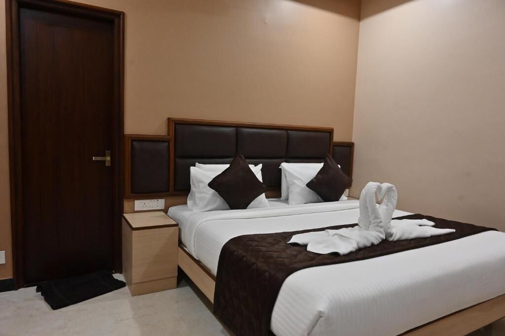 A neatly made bed with a brown headboard, a bedside table, and a door to the left.