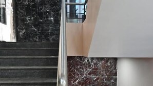 Eine Treppe mit schwarzen Marmorstufen und einem Metallgeländer, die zu einer unteren Ebene führt.