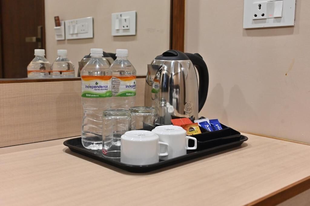A tray with water bottles, a coffee maker, and cups on a hotel counter.