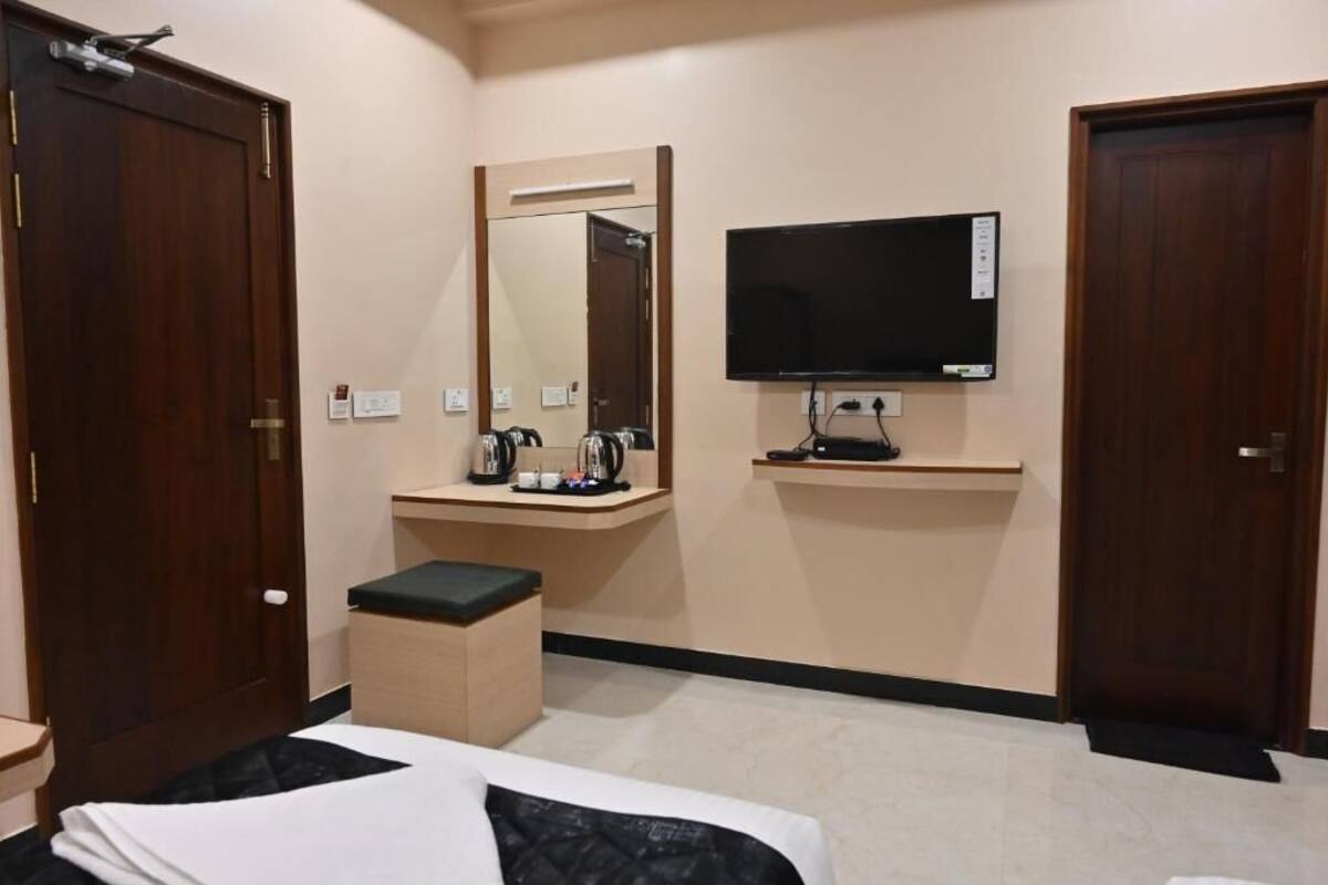 Una habitación de hotel con una cama, un pequeño escritorio con espejo, un televisor y una zona de café.