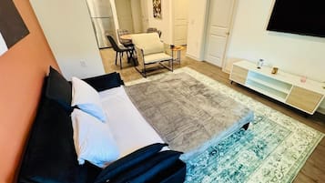 Un dormitorio con una cama, televisión, escritorio y una silla.