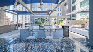 Et udendørs køkkenområde med jacuzzi, grill og siddepladser.