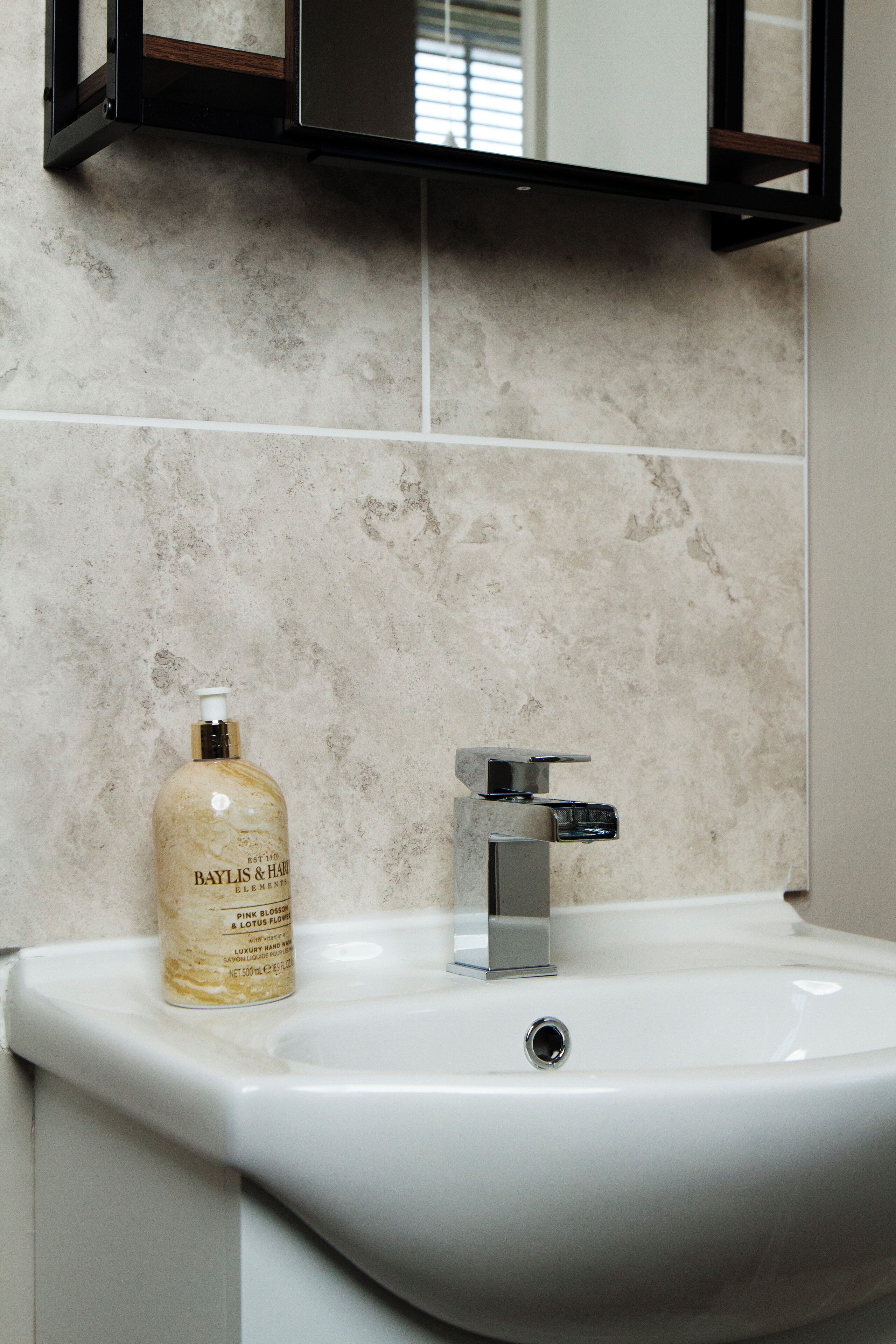 Un lavabo de salle de bain avec un flacon de lotion Baylis & Hayes et un robinet chromé.