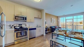 A modern kitchen with stainless steel appliances, wooden cabinets, and a dining area with a table set for four. - Great Charming stay (Stamford)