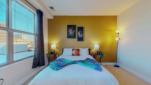 A hotel room with a large bed, two bedside lamps, a window with curtains, and two wall-mounted artworks. - Great Charming stay (Stamford)