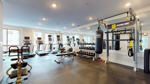 A gym with treadmills, elliptical machines, a punching bag, and a TRX suspension trainer. - Great Charming stay (Stamford)