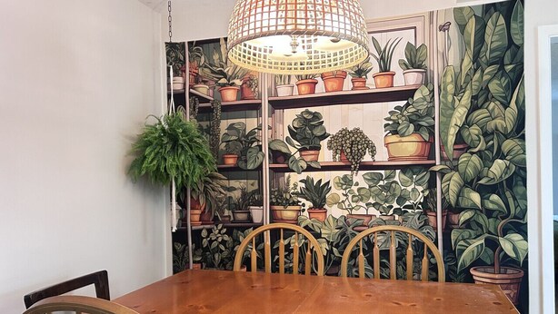 Et spiseområde med et træbord og stole, omgivet af reoler med plantede planter.