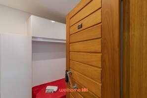 Ein Zimmer mit einer Holztür, die die Nummer 212 trägt, einem roten Bett und einem weißen Kleiderschrank.