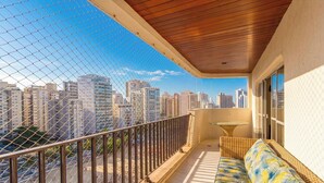 Een balkon met uitzicht op de stad, een houten plafond en een rieten zittaak.