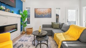 Una sala de estar moderna con chimenea, un sofá, una mesa de centro y un cuadro grande en la pared.