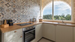 A kitchen with a patterned backsplash, a window with a view, a sink, and wooden countertops. - Casale Calia - Carovigno (Carovigno)
