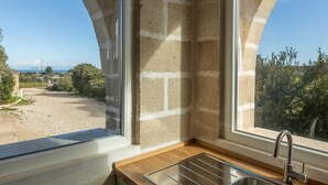 A kitchen with a window overlooking a garden and a view of the sea. - Casale Calia - Carovigno (Carovigno)