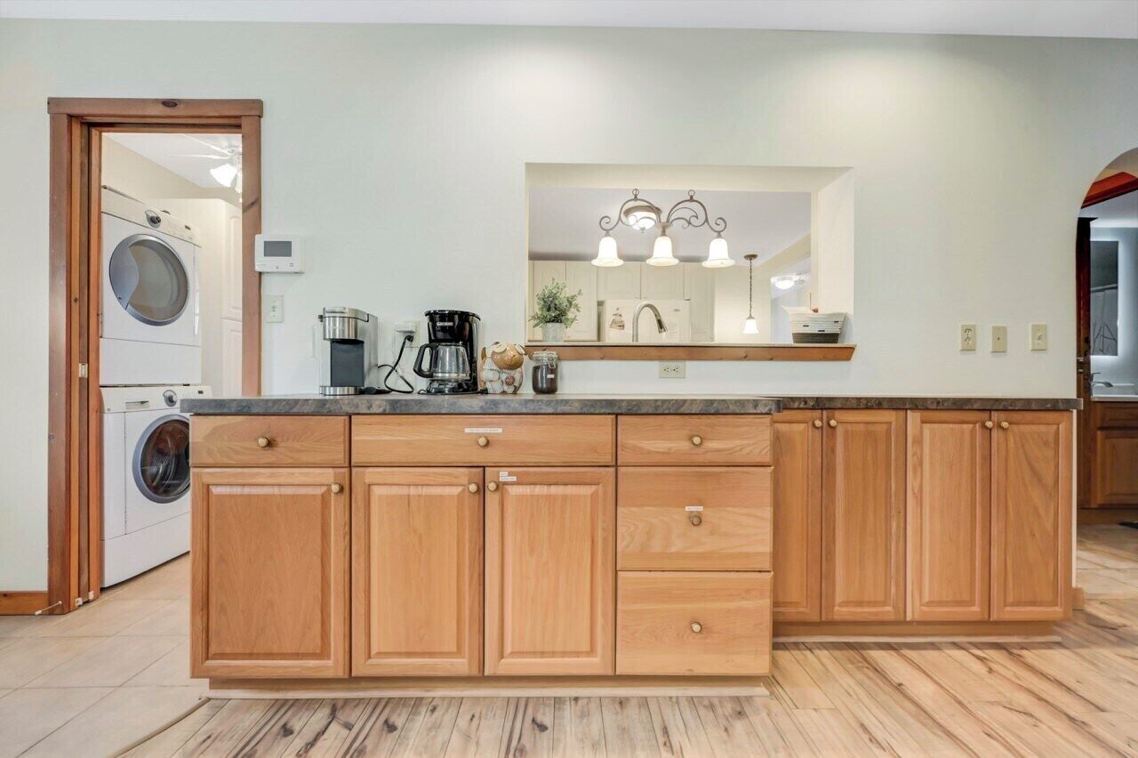 A modern kitchen with wooden cabinets, a built-in oven, and a large island with a sink.