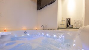 Un baño moderno con una bañera grande, un espejo y un estante con artículos de aseo.