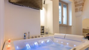 Un baño moderno con una bañera grande, cabina de ducha con mampara de vidrio y ventana que proporciona luz natural.