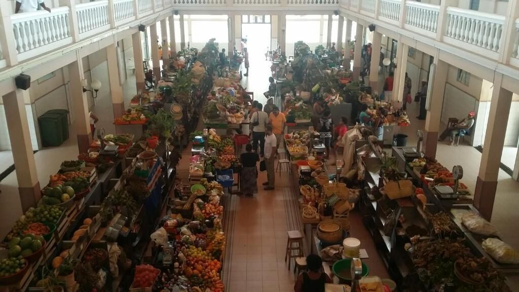 A bustling indoor market with multiple stalls selling fresh produce and goods.
