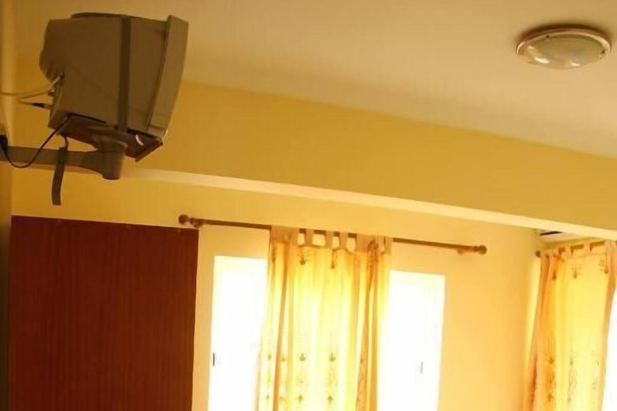 Habitación de hotel con dos camas, una silla y un televisor.