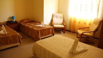 A hotel room with two beds, a chair, and a nightstand with a lamp.