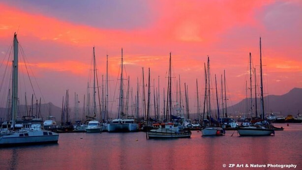 Un puerto deportivo con varios veleros amarrados al atardecer.