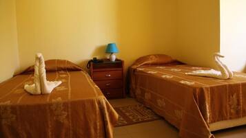 A hotel room with two beds, a nightstand with a lamp, and a telephone.