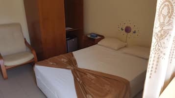 Habitación de hotel con cama, una silla, armario, mesita de noche y un adorno en la pared.