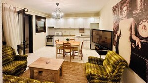 A compact living space with a dining area, kitchenette, and a television.
