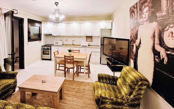 A living room with a dining table, chairs, a TV, and a sofa.