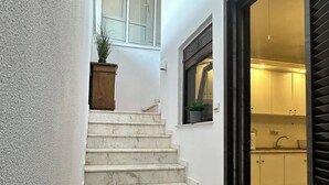 A staircase leading to a kitchen with white walls and a window.