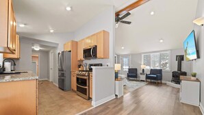A modern kitchen with wooden cabinets, stainless steel appliances, and a large island. - Relax & Recharge | Fire pit, Game Room, Near Torch Lake (Bellaire)