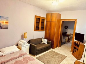 Un salon chaleureux avec un canapé, un meuble pour la télévision, une armoire en bois et un tableau représentant un coucher de soleil.