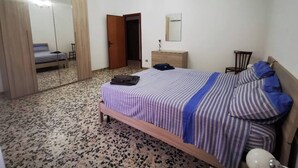 Une chambre à coucher comprenant un lit, une table de chevet, un miroir et une armoire.