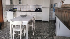 Une cuisine de taille réduite avec des meubles blancs, un plan de travail noir et un pare-feu en carreaux.