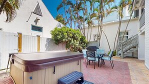 Un giardino sul retro con vasca idromassaggio, area salotto esterna e una scala che conduce a un secondo piano.